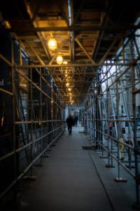 A person walking under a scaffolding tower