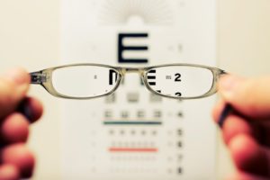 A pair on eyeglasses being held up in front of an eye exam