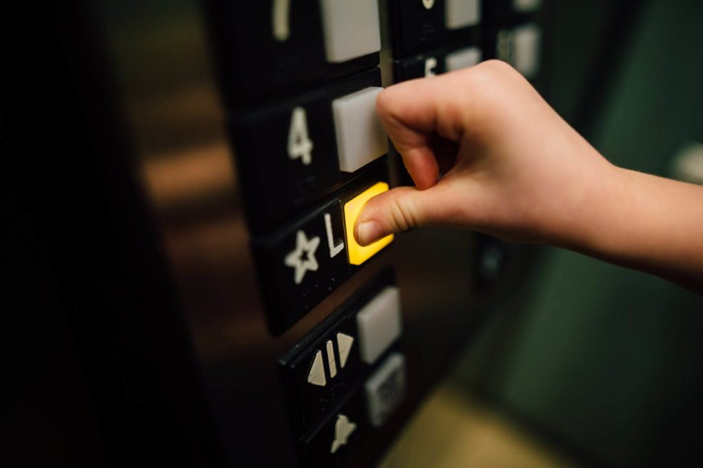 A person pushing the L button in an elevator